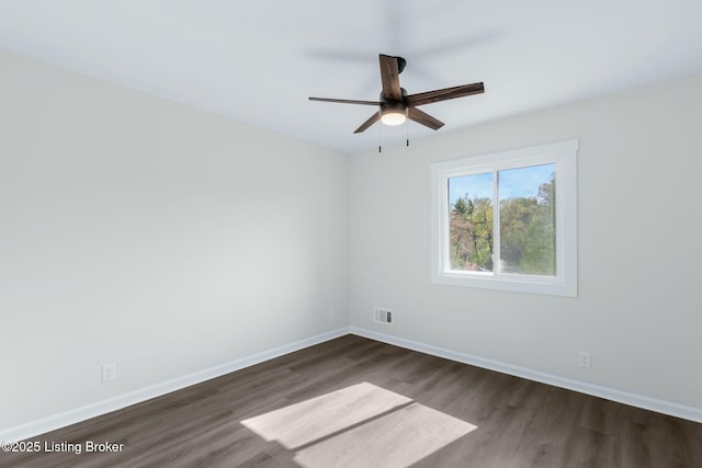 empty room featuring baseboards, visible vents, dark wood-style floors, and ceiling fan