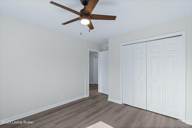 unfurnished bedroom with baseboards, a ceiling fan, wood finished floors, and a closet