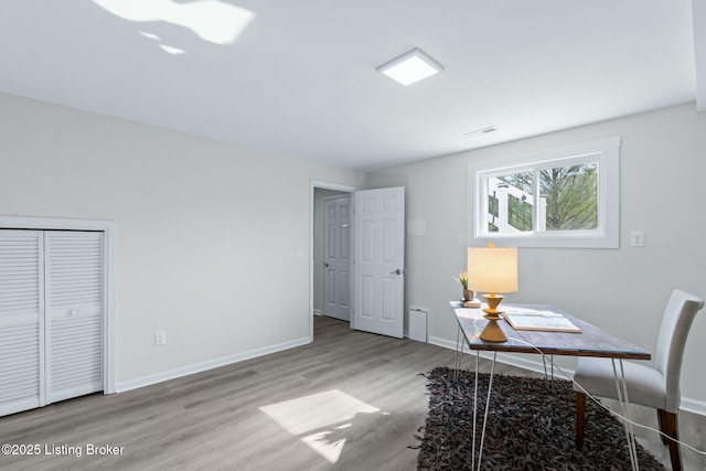 office space featuring wood finished floors, visible vents, and baseboards