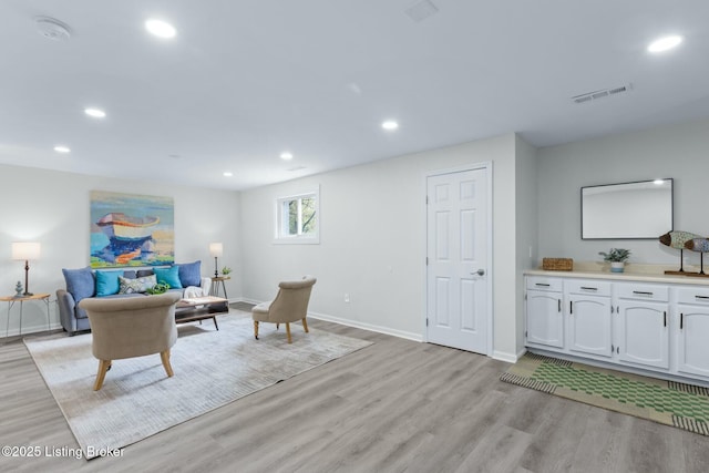 living room featuring baseboards, light wood-style flooring, visible vents, and recessed lighting