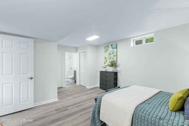 bedroom featuring wood finished floors, baseboards, connected bathroom, and a closet