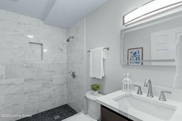 full bathroom featuring a tile shower, toilet, and vanity