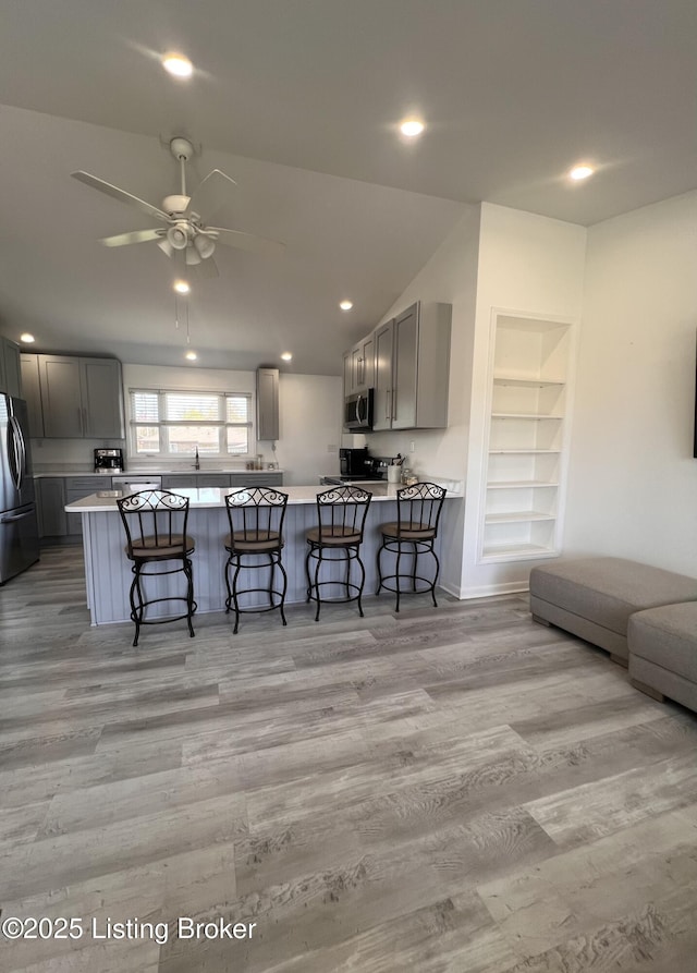 living area with recessed lighting, vaulted ceiling, light wood-style floors, built in shelves, and ceiling fan