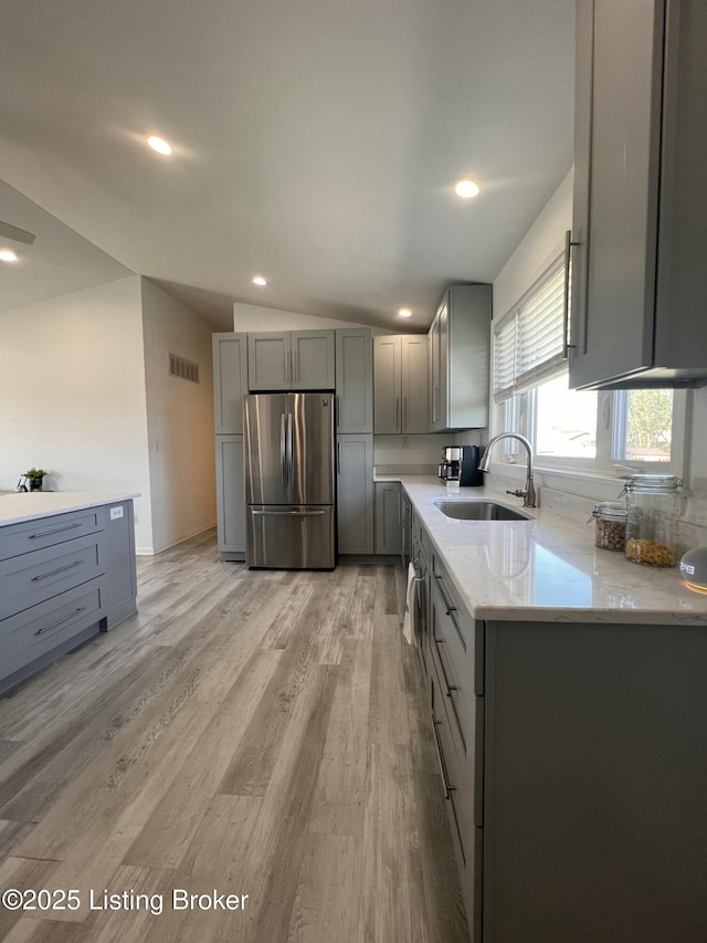 kitchen featuring visible vents, gray cabinets, a sink, freestanding refrigerator, and light wood-style flooring