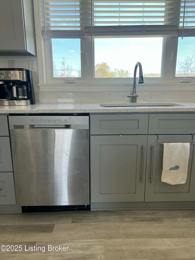 kitchen with dishwasher, a sink, light wood-style floors, and gray cabinets