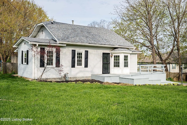 back of house featuring a wooden deck, fence, a yard, and roof with shingles