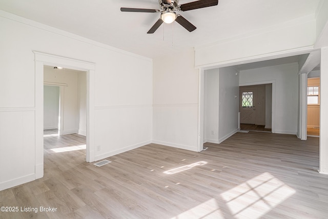 empty room featuring baseboards, visible vents, light wood-style floors, and ceiling fan
