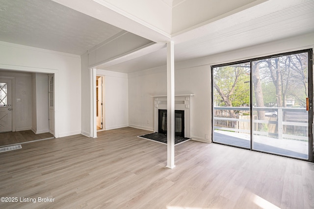 unfurnished living room featuring a fireplace with flush hearth, a healthy amount of sunlight, and light wood-style flooring