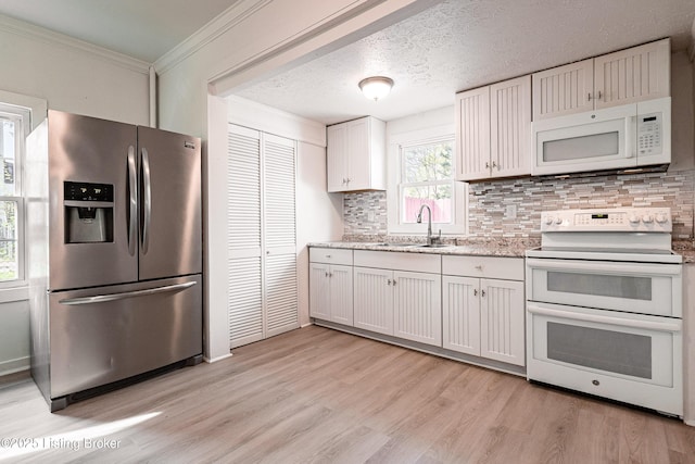 kitchen with backsplash, light wood-type flooring, a sink, and white appliances