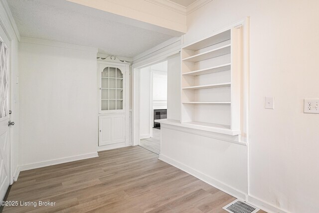 unfurnished dining area featuring baseboards, light wood-style floors, visible vents, and a fireplace