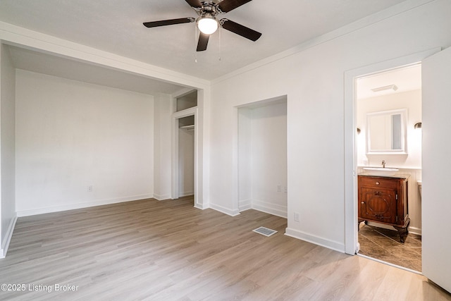 unfurnished bedroom featuring visible vents, light wood-style floors, ensuite bath, a closet, and baseboards