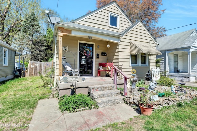 bungalow-style home with a porch, a front lawn, and fence