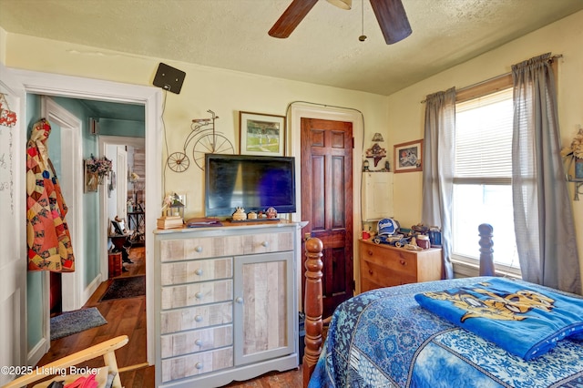 bedroom with a ceiling fan, a textured ceiling, and dark wood finished floors