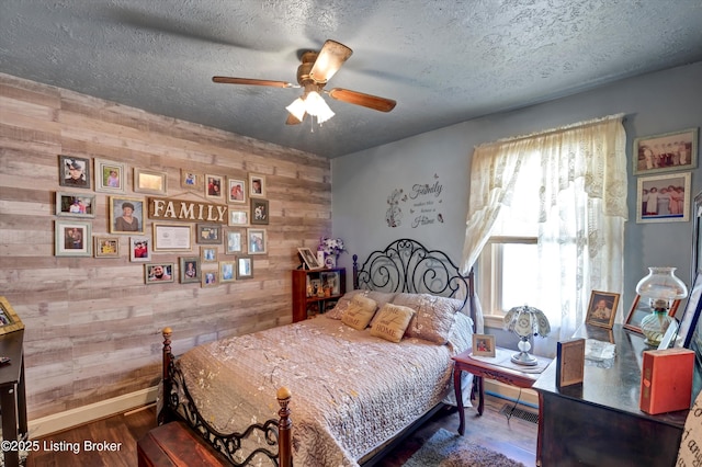 bedroom with baseboards, wood finished floors, multiple windows, and wooden walls