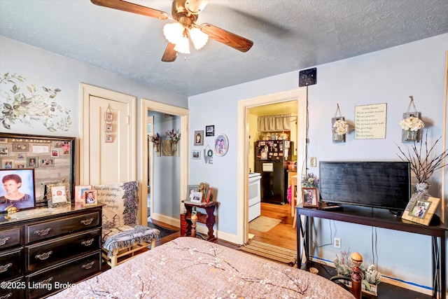 bedroom with a textured ceiling, freestanding refrigerator, a ceiling fan, wood finished floors, and ensuite bath