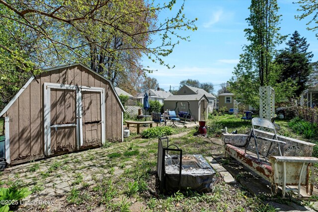 view of yard with a fire pit, an outbuilding, a storage shed, and fence