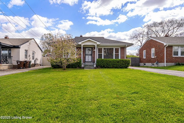 bungalow-style house with a front yard, fence, and brick siding
