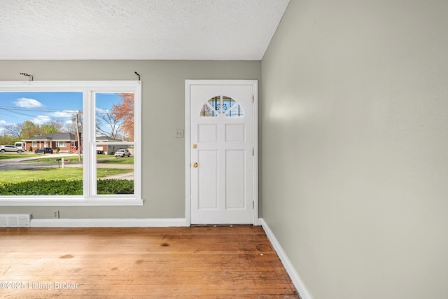 entryway featuring a textured ceiling, wood finished floors, baseboards, and visible vents