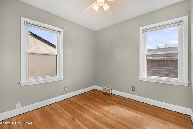 unfurnished room featuring baseboards, light wood finished floors, and plenty of natural light
