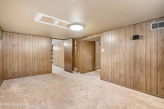 finished below grade area featuring wood walls, carpet, and visible vents