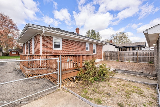 exterior space with a chimney, fence, a deck, and brick siding