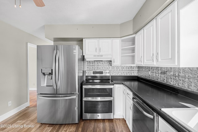 kitchen featuring white cabinetry, open shelves, dark countertops, under cabinet range hood, and stainless steel appliances