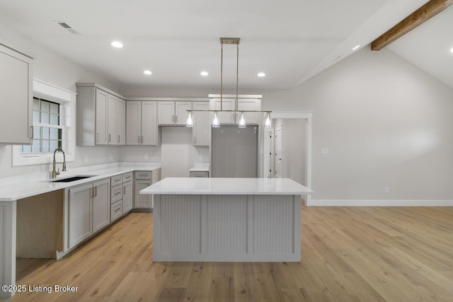 kitchen featuring a sink, freestanding refrigerator, gray cabinetry, light wood-style flooring, and a kitchen island