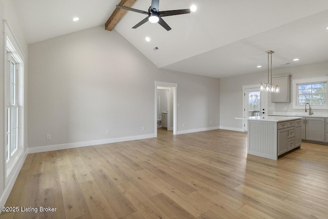 unfurnished living room featuring beamed ceiling, light wood finished floors, and a ceiling fan
