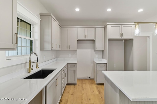 kitchen featuring recessed lighting, gray cabinetry, light wood finished floors, and a sink