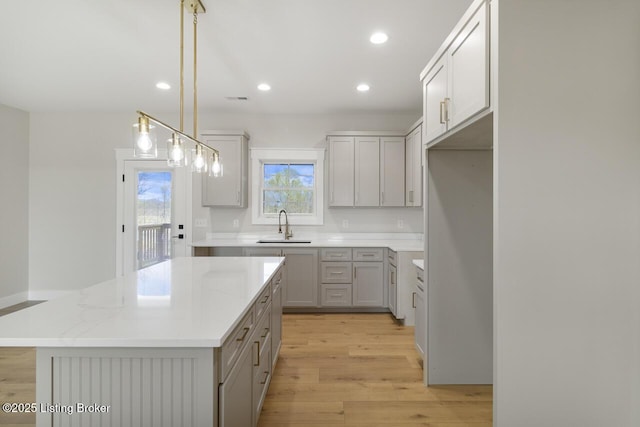 kitchen with recessed lighting, gray cabinetry, light wood finished floors, and a sink