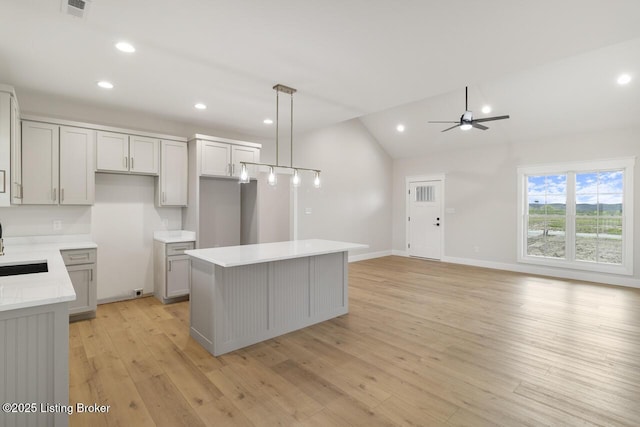 kitchen with ceiling fan, recessed lighting, vaulted ceiling, and a kitchen island