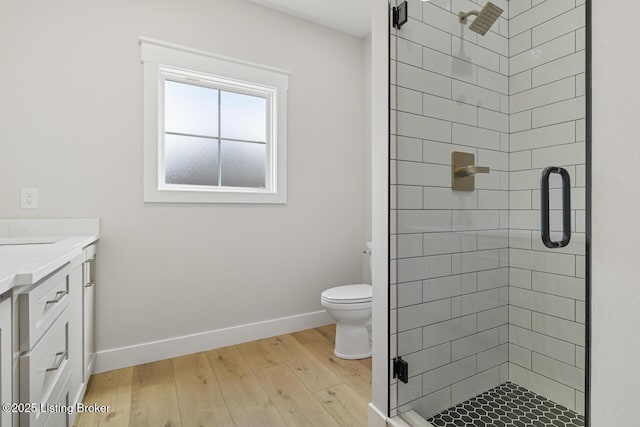 full bath featuring vanity, baseboards, toilet, a shower stall, and wood finished floors