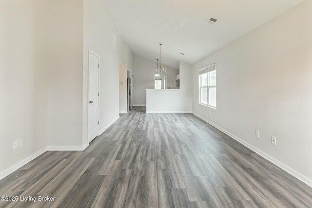 unfurnished dining area featuring baseboards, lofted ceiling, and dark wood finished floors
