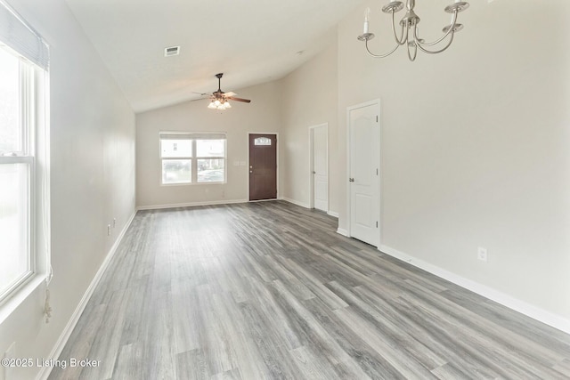 unfurnished living room with visible vents, ceiling fan with notable chandelier, wood finished floors, and lofted ceiling