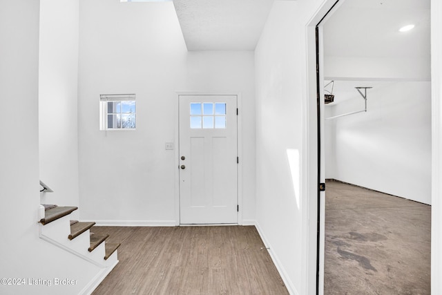 entryway with wood finished floors, baseboards, and stairway