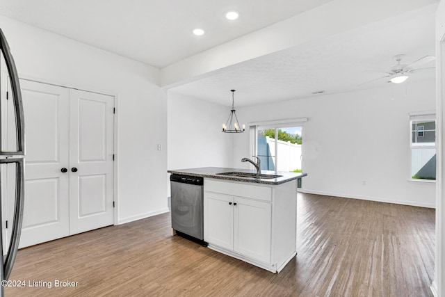 kitchen with wood finished floors, stainless steel dishwasher, a sink, and white cabinetry
