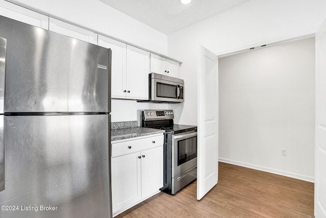 kitchen with light wood-style floors, appliances with stainless steel finishes, baseboards, and white cabinetry