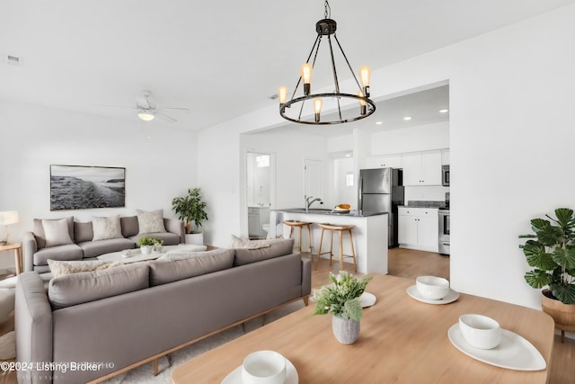 dining area featuring light wood finished floors, recessed lighting, and ceiling fan with notable chandelier