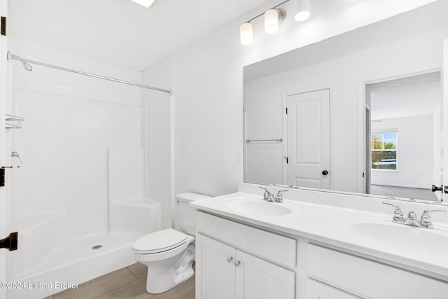 bathroom with walk in shower, double vanity, a sink, and toilet