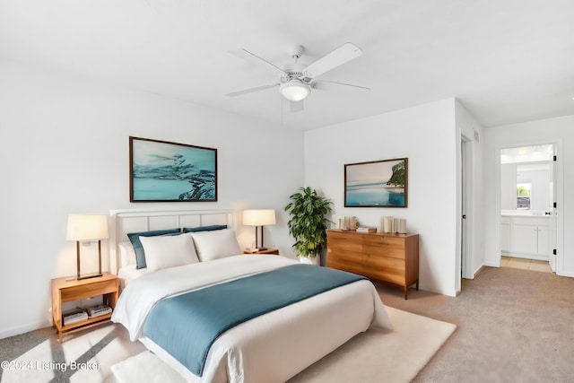 bedroom with light colored carpet, ceiling fan, and connected bathroom