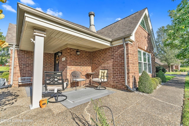 back of house featuring brick siding and a shingled roof