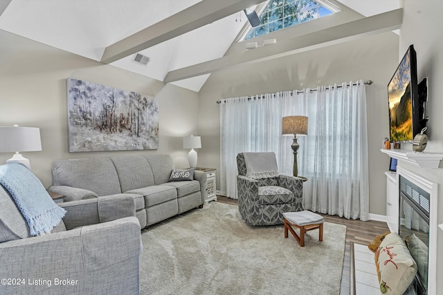 living room with high vaulted ceiling, wood finished floors, a glass covered fireplace, baseboards, and visible vents