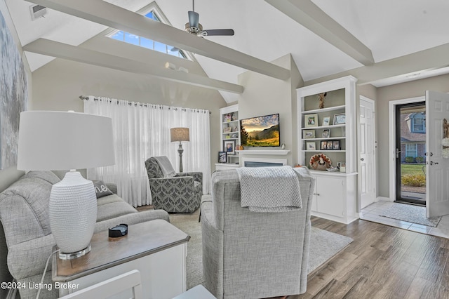 living area with wood finished floors, a healthy amount of sunlight, high vaulted ceiling, and ceiling fan