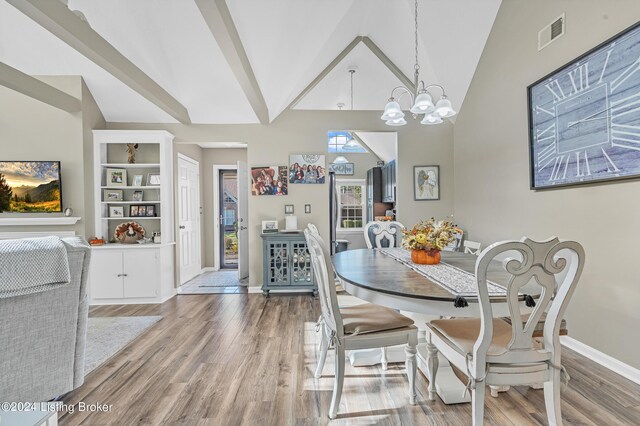dining space featuring vaulted ceiling, baseboards, visible vents, a chandelier, and wood finished floors