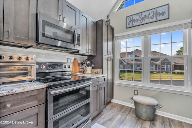 kitchen featuring baseboards, appliances with stainless steel finishes, tasteful backsplash, and a wealth of natural light