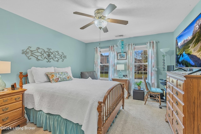 bedroom with light carpet, a ceiling fan, and visible vents