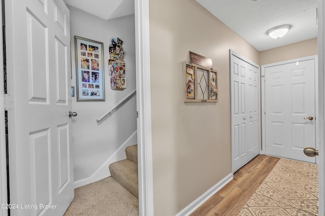 hall featuring baseboards, light wood-style floors, and stairs