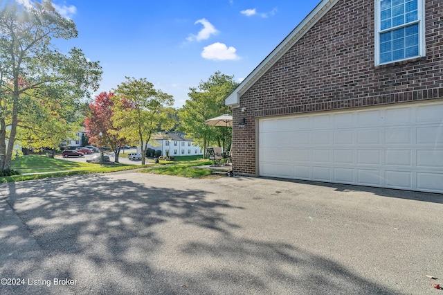 view of side of home with brick siding, driveway, and a garage