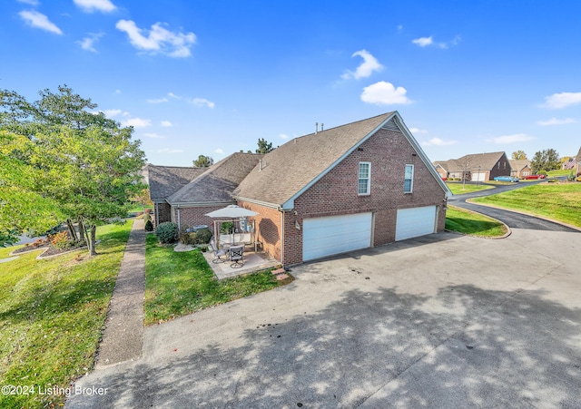 view of side of home featuring brick siding, an attached garage, a lawn, and driveway