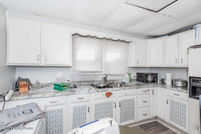kitchen with white cabinets, black microwave, and a sink